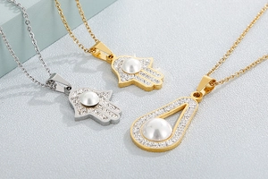 Detailed view of gold and silver Hamsa Hand pendants with white pearls and crystals