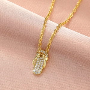 Macro-opname van een gouden slipper-hanger ketting met zirkoonstenen op roze stof