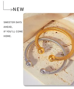 Detail view of gold and silver twisted cable cuff bracelets on textured stone base