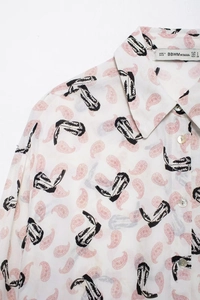 Detailed close-up of a vintage print shirt collar with intricate boot and paisley patterns