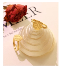 Detailed view of two gold Chinese Fu character rings on a ceramic spiral gift stand
