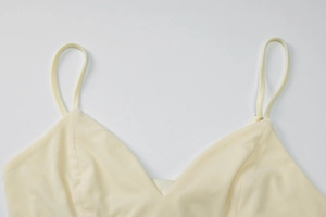 Detailed macro view of cream-colored V-neck camisole top with thin spaghetti straps
