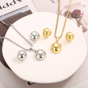 Polished gold and silver ball pendant necklaces with matching earrings on tray