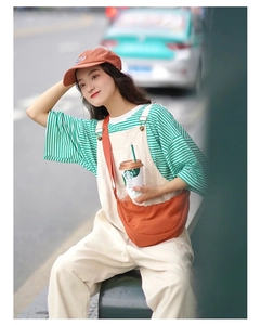 Summer casual outfit featuring an orange nylon crescent crossbody bag with a green striped tee