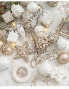 Flat lay of white and gold Christmas tree ornaments with festive warm string lights