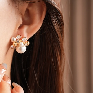 Close-up detail of luxury flower pearl cluster earrings with gold base and zircons