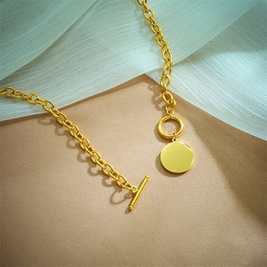 Gold-plated titanium steel necklace with OT buckle and round pendant on fabric background