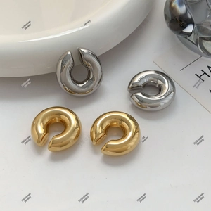 Detailed close-up of thick hollow U-shaped ear cuffs in polished gold and silver finishes