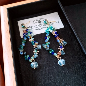 Detail of diamond-studded glass tassel earrings with blue beads in a jewelry box