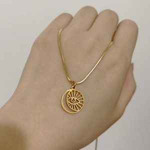 Detail of 18K gold snake chain necklace with hollow sun evil eye pendant on hand