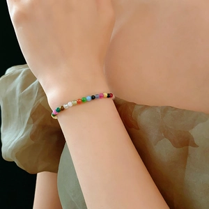 Close-up of a colorful beaded gemstone bracelet worn on a woman's wrist with warm lighting