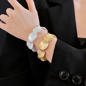 Detailed view of layered circular metal cuff bracelets in gold and silver matte finishes