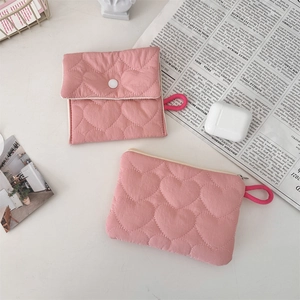 Close-up of pink heart quilted sanitary pouch and zipper bag on newspaper background