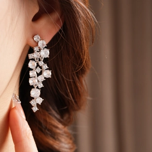 Close-up of elegant silver tassel earrings with irregular zircon stones on a model