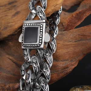 Macro detail of vintage steel chain bracelet with floral engraving and black gemstone