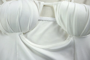 Close-up of ruched cup details and precise topstitching on a white cutout backless dress