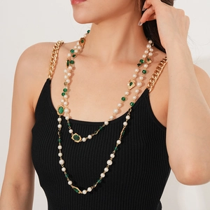 Detail of vintage layered pearl necklace with green gemstones on female model