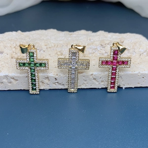 Detailed view of 18k gold cross pendants with green, clear, and red zircon stones