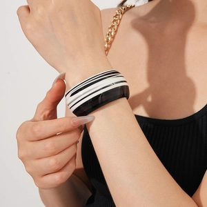 Close-up of black and white striped acetate cuff bracelet worn on female wrist