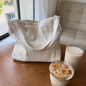 Borsa tote minimalista in tela beige con fibre colorate su un tavolo da caffè