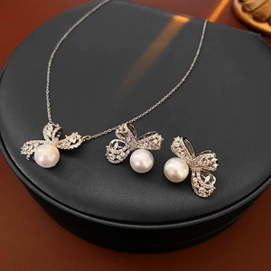Détail de l'ensemble bijoux avec nœud en argent et perles sur présentoir noir