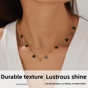 Close-up of gold plated stainless steel necklace with black heart pendants and zircons