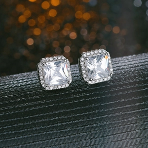Macro shot of silver square stud earrings with clear halo crystals on dark bokeh background