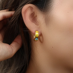 Detailed view of model wearing gold hoop earrings with colorful oil drip flower patterns