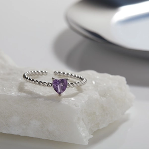 Macro detail of twisted silver band ring featuring a heart-shaped purple gemstone