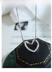Detailed close-up of a silver heart pendant necklace on a black jewelry box