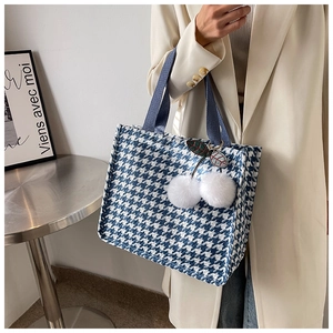 Detail view of woven houndstooth tote bag featuring a cute plush cherry charm accessory