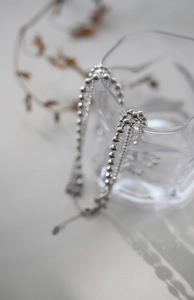 Detailed view of silver beaded chain necklace with toggle clasp on a clear glass rim