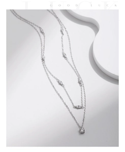 Detail of a silver double-layered S925 necklace featuring a sparkling solitaire pendant