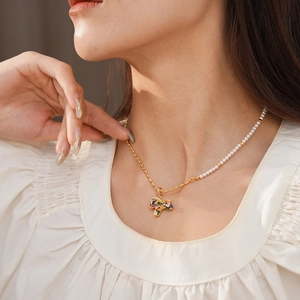 Detail of half-pearl half-gold chain necklace with colorful gemstone pendant on model