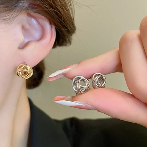 Detailed view of intertwined twist design earrings in polished gold and silver finishes