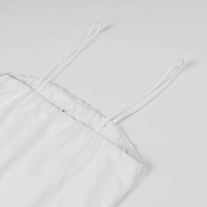 Close-up of thin shoulder straps and square neckline on a white pleated dress with S label