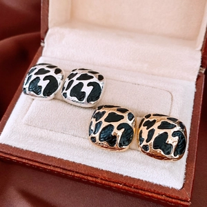 Detailed view of square cow print enamel stud earrings in gold and silver metal finishes
