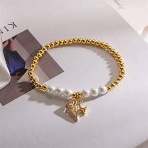 Detail of gold beaded bracelet with pearls and a crystal-encrusted fish charm pendant