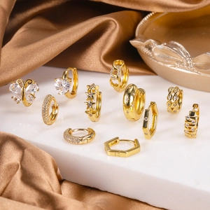 Detailed close-up of gold butterfly and heart stud earrings with cubic zirconia on marble