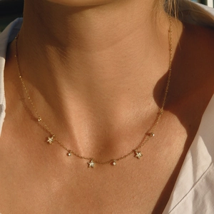 Close-up of gold titanium steel necklace with star and round zircon pendants on model
