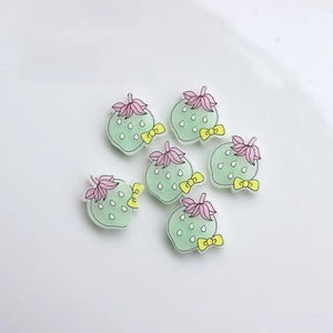 Detailed view of six mint green resin strawberry charms with pink leaves and yellow bows