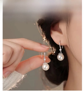 Nahaufnahme eleganter 999er Sterlingsilber-Ohrhänger mit weißen Perlen am Modell