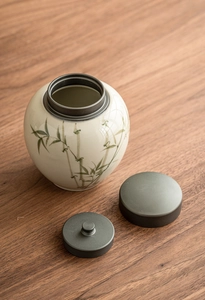 Detail view of cream ceramic tea canister with bamboo patterns and alloy double lids