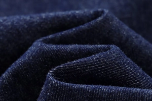 Macro shot of dark blue denim fabric texture showing premium twill weave and fiber detail