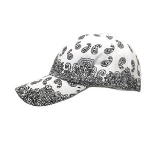 Detailed close-up of white twill cotton baseball cap with black paisley pattern and curved brim