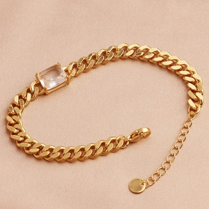 Detail of gold-plated Cuban chain bracelet with a rectangle zircon on silk background