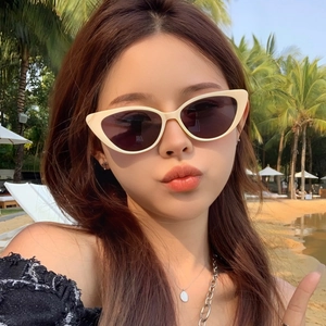 Fashionable beige cat-eye sunglasses with dark grey lenses for a beach vacation look
