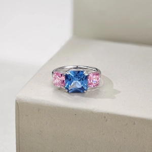 Macro shot of silver ring featuring square blue center stone and pink side stones