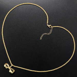 Detailed view of heart-shaped layout of gold bow necklace on textured black background