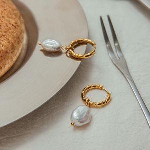 Elegant gold baroque pearl drop earrings on a silver plate for a luxury lifestyle look